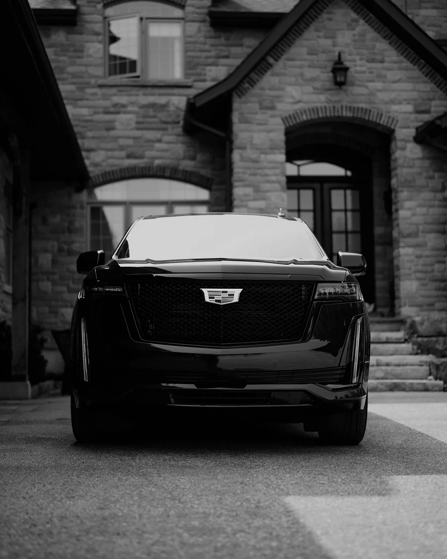 Black Cadillac Escalade waiting outside an upscale residence